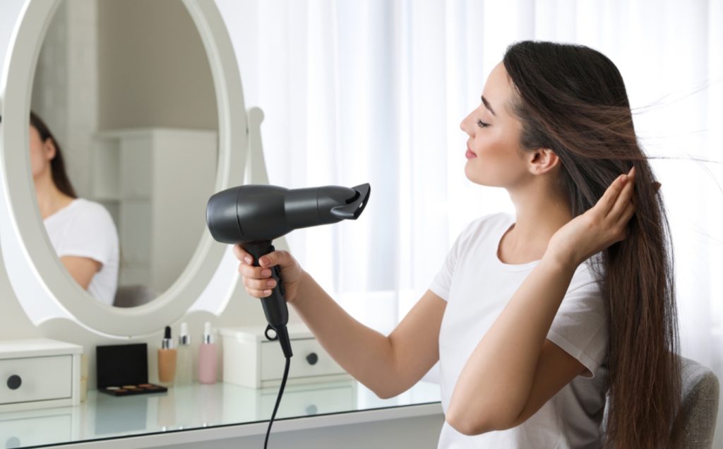 ドライヤーで乾かす女性（ロングヘア）